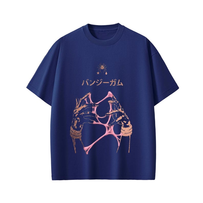 Pu&ograve; includere: T-shirt blu navy con un design grafico. Il design include il testo giapponese "バンジーガム", un'illustrazione stilizzata di mani e materiale rosa appiccicoso, una stella e un grafico di ragno.