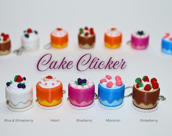 May include: A collection of miniature cake-shaped clickers in various colors, each topped with different decorative elements like strawberries, blueberries, and macarons. The text "Cake Clicker" is displayed above the cakes.
