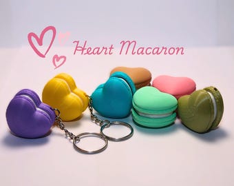 May include: A set of six heart-shaped macaron keychains in various colors, including purple, yellow, blue, green, pink, and brown. The keychains are attached to a silver chain with two silver rings.