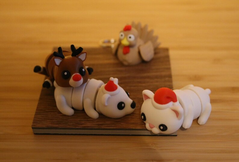 May include: A set of four Christmas-themed figurines: a reindeer, a polar bear, a cat, and a turkey. The figurines are made of a soft, pliable material and are painted in bright, festive colors.