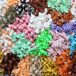 May include: A large collection of colorful, small, articulated plastic animal figurines. The animals include giraffes, pandas, fish, and more.
