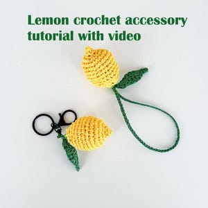 Puede incluir: Dos llaveros de limón tejidos a crochet con hojas verdes. El llavero de la izquierda tiene un anillo de metal negro. El llavero de la derecha tiene un cordón largo de crochet verde.