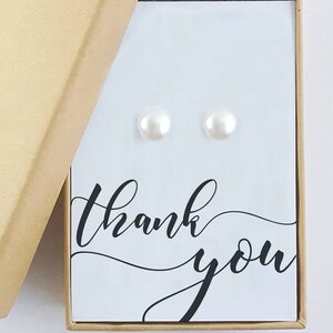 May include: A small, white gift box with a thank you message on the front. The box is open and contains a pair of pearl earrings.
