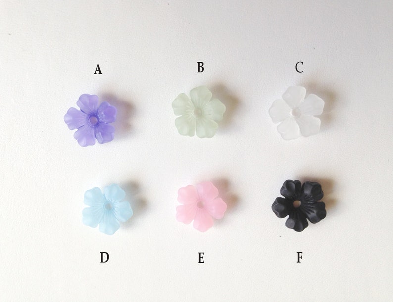 May include: Six flower-shaped beads in different colors: purple, light green, clear, light blue, pink, and black.