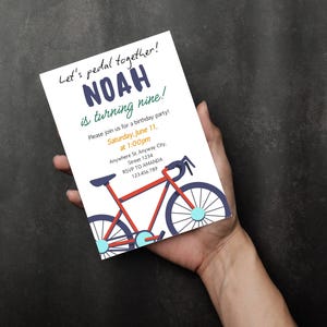 May include: A birthday party invitation featuring a red bicycle illustration. The invitation includes the text "Let's pedal together!" and details for Noah's ninth birthday, including the date, time, and location. The invitation is held in a hand.