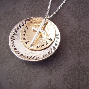 May include: A silver and gold necklace with a cross charm and a round pendant with the names "Emily, James, Sarah, Andy, and Margaret" engraved on it.
