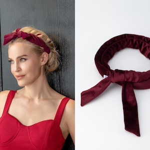 May include: A burgundy velvet headband with a bow. The headband is tied in a knot at the back.