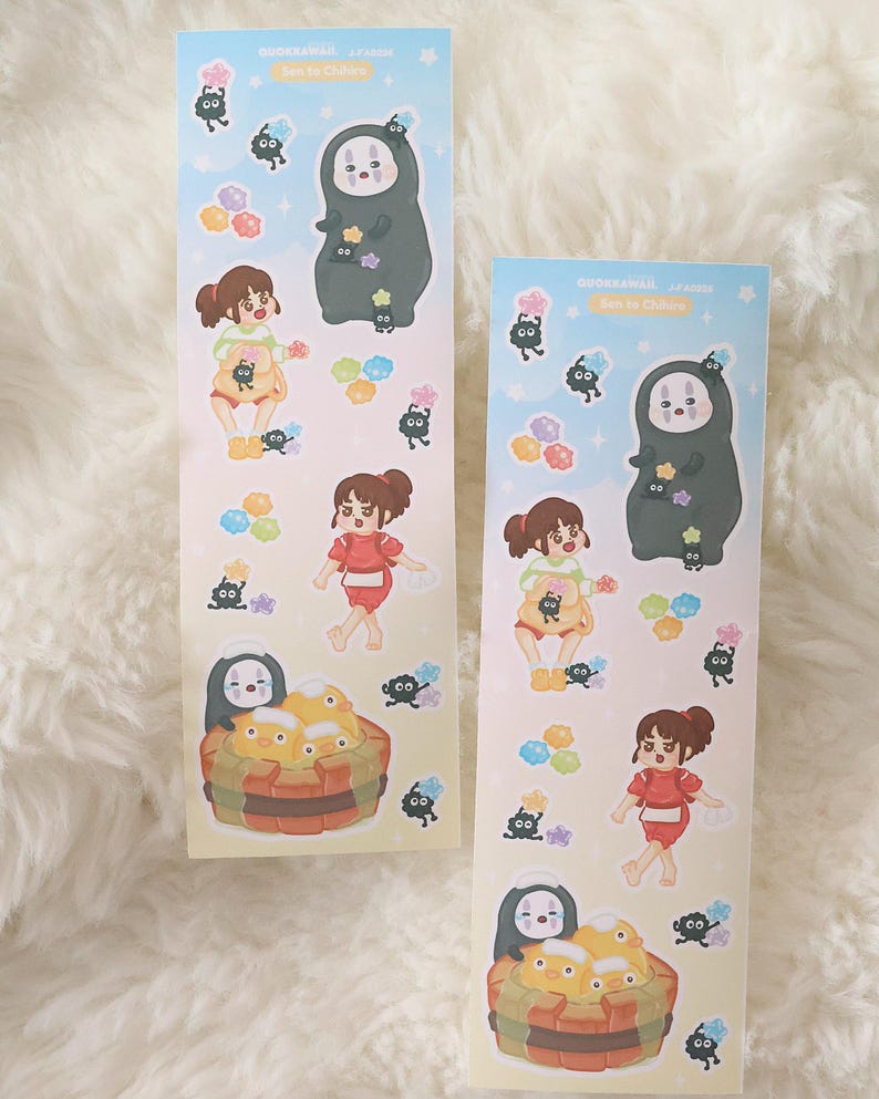 May include: Two decorative stickers featuring characters from "Spirited Away." The stickers have a light blue background with illustrations of characters, including No-Face, Chihiro, and soot sprites. The stickers are rectangular and have Japanese text at the top.