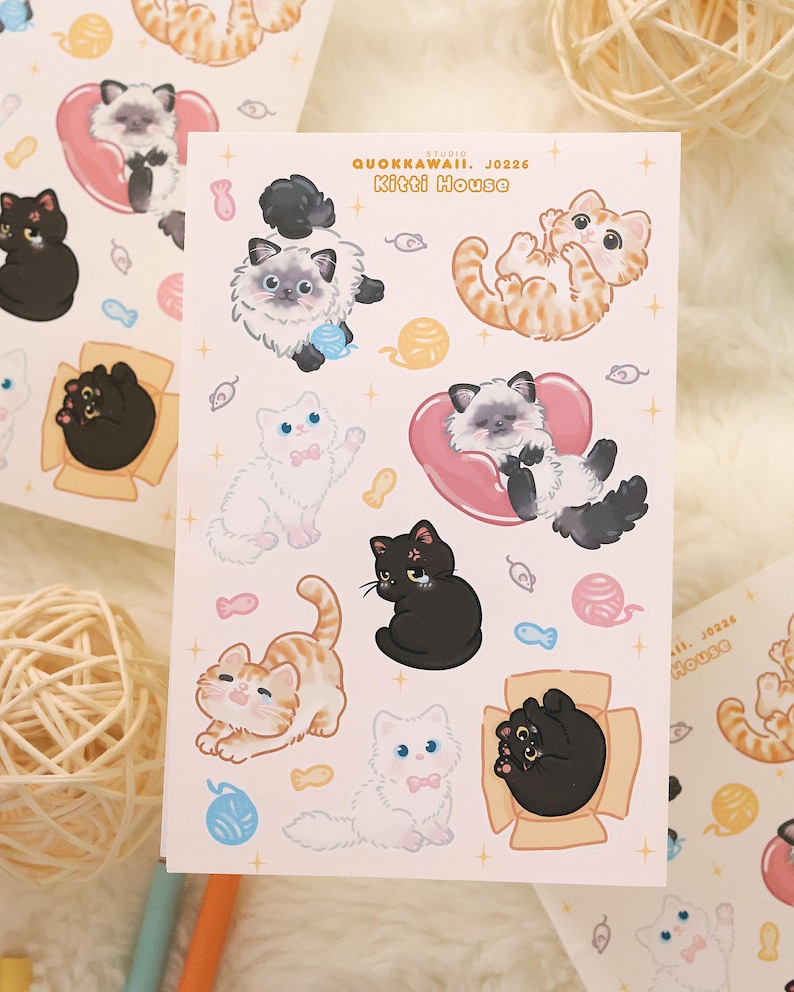 May include: Sheets of stickers featuring various cartoon cats in playful poses. The stickers include cats in boxes, with yarn balls, and hearts. The text "QUOKKAWAII. J0226 Kitti House" is printed on the sheet.