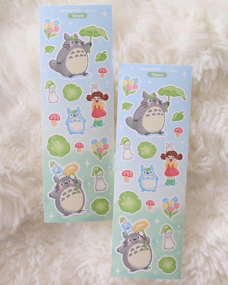 May include: Two sticker sheets with Totoro characters on a pale blue backdrop. The stickers depict Totoro, a girl in a red dress, and forest-themed illustrations. The text "Totoro" is printed on the sheets.