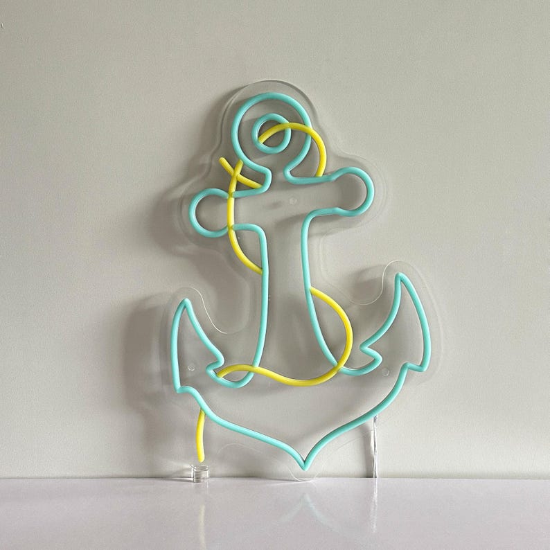 Puede incluir: Una l&aacute;mpara de ne&oacute;n con forma de ancla. El ancla es de color azul claro con detalles amarillos. Est&aacute; montada sobre una base de acr&iacute;lico transparente. Ideal para la decoraci&oacute;n de paredes.