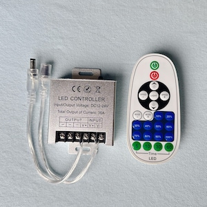 May include: An LED controller with a remote control. The silver controller box has text that reads "LED CONTROLLER" and "Input/Output Voltage: DC12-24V". The white remote has buttons for speed, light, and mode, and a timer.
