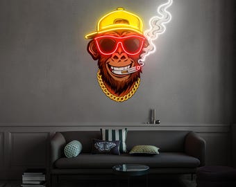 May include: A neon sign shaped like a monkey wearing a yellow cap, red sunglasses, and a gold chain. The monkey is smoking a cigarette, with white smoke rising. The sign is mounted on a gray wall.