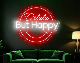 May include: A circular neon sign mounted on a dark wall featuring a bright red outline of a circle and a smiling mouth. The text "Delulu" is written in a white cursive script above the text "But Happy" in a bold white sans-serif font.