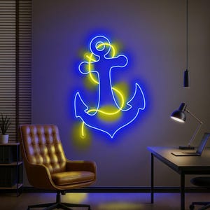 Puede incluir: Un letrero de ancla de ne&oacute;n azul con detalles amarillos est&aacute; montado en una pared gris. El arte de tem&aacute;tica n&aacute;utica est&aacute; iluminado, creando un brillo vibrante. La habitaci&oacute;n cuenta con una silla de cuero marr&oacute;n, un escritorio y un port&aacute;til.