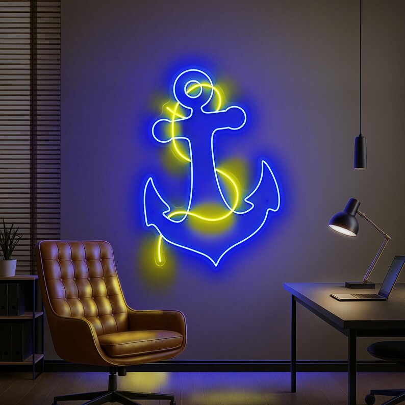 Puede incluir: Un letrero de ancla de ne&oacute;n azul con detalles amarillos est&aacute; montado en una pared gris. El arte de tem&aacute;tica n&aacute;utica est&aacute; iluminado, creando un brillo vibrante. La habitaci&oacute;n cuenta con una silla de cuero marr&oacute;n, un escritorio y un port&aacute;til.