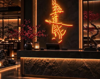 May include: A bright orange neon sign featuring Japanese kanji characters mounted on a dark, textured stone wall above a reception desk. The sign glows with a warm light, positioned centrally in a dimly lit space with decorative red floral accents.