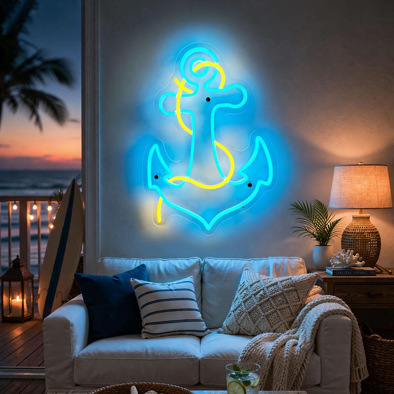 Puede incluir: Un letrero de ne&oacute;n brillante con forma de ancla en azul y amarillo cuelga de una pared sobre un sof&aacute; blanco. La decoraci&oacute;n de tem&aacute;tica n&aacute;utica incluye cojines, una manta y una l&aacute;mpara. La escena est&aacute; ambientada en un sal&oacute;n con vistas al mar al atardecer.