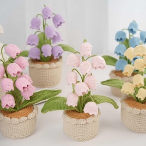 May include: Five crocheted lily of the valley plants in pots. The plants are in different colors: white, pink, purple, light blue, and yellow.