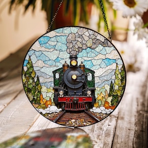 May include: A stained glass window hanging on a chain, depicting a vintage steam locomotive with black, green, and red details, travelling through a landscape with trees and clouds.