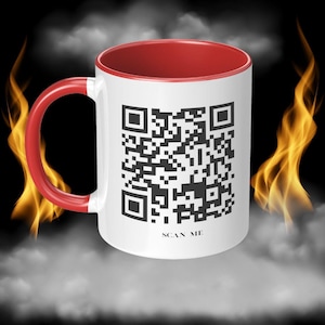Pode incluir: Caneca de cerâmica branca com interior e alça vermelhos. A caneca apresenta um grande código QR em preto e branco, com a inscrição "SCAN ME" abaixo. O fundo inclui chamas e fumaça.