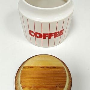 May include: A white ceramic mug with a black handle and the text "But First, Coffee" in a handwritten style. The mug is on a white surface. The mug is approximately 4 inches tall.