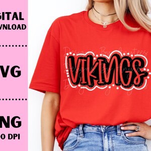 May include: A red t-shirt with the word "VIKINGS" in black outlined in white. The shirt is being worn by a person with long blonde hair.