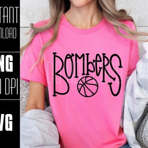 May include: Pink t-shirt with the text "Bombers" in black with a basketball graphic.