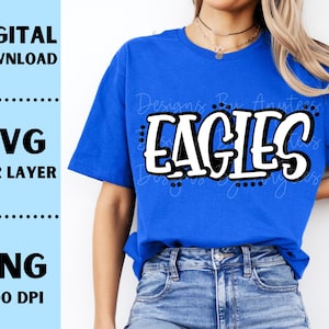 Op de afbeelding: Een koningsblauw t-shirt met het woord "EAGLES" in een vetgedrukte, witte, omlijnde letter. Het shirt heeft ook de tekst "Designs By Anytees!" in een scriptletter. De afbeelding bevat ook de tekst "DIGITAL DOWNLOAD", "SVG 1 & 2 LAYER" en "PNG 300 DPI".