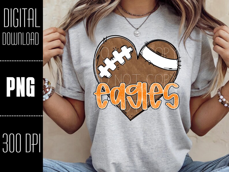 Puede incluir: Camiseta gris claro con un dise&ntilde;o de bal&oacute;n de f&uacute;tbol en forma de coraz&oacute;n y la palabra "Eagles" en naranja. El bal&oacute;n es marr&oacute;n con cordones blancos y una franja blanca. A la izquierda, el texto dice "DIGITAL DOWNLOAD", "PNG" y "300 DPI".