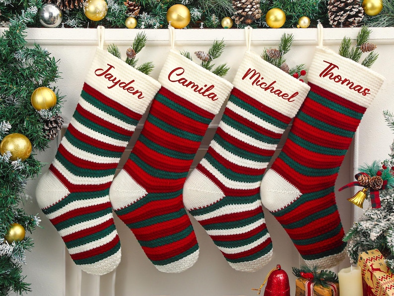 May include: Four Christmas stockings with names embroidered in red: Jayden, Camila, Michael, and Thomas. The stockings are red, green, and white striped with a white cuff and toe. Festive holiday decor.