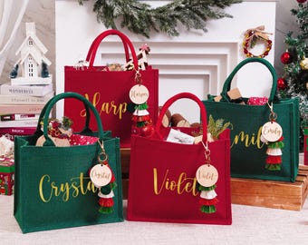 May include: Four personalized Christmas gift bags in red and green. Each bag has a gold handle and a wooden tag with a name and tassel. The bags are filled with gifts and decorations, perfect for the holiday season.