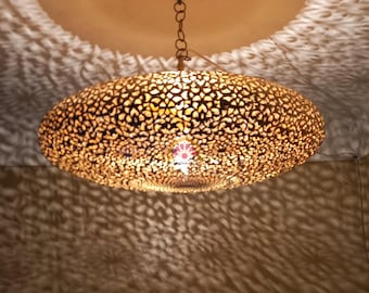 May include: A large, round, gold-colored ceiling light fixture with intricate cut-out designs. The light casts a patterned shadow on the ceiling.