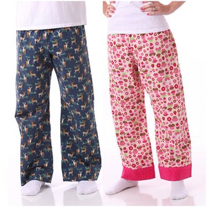 May include: Two pairs of pyjama trousers, one with a blue background and a brown deer print, and the other with a pink background and a cupcake print.