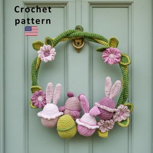 May include: A handmade crochet Easter wreath with bunny and egg decorations. The wreath is green with pink and white flowers and bunny figures. The text "Crochet pattern" is at the top.