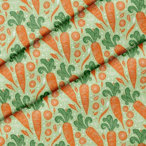 May include: Fabric with a repeating pattern of orange carrots with green tops on a light green background. The design includes carrot slices and small white dots.