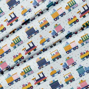 May include: A repeating pattern of colorful toy trains on a white background. The trains are in various colors, including blue, yellow, pink, and green, with black wheels and accents. The fabric has a dotted texture.