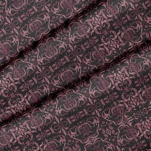 Könnte beinhalten: Ein schwarzer Stoff mit einem sich wiederholenden Damastmuster in einem gedämpften Dunkelviolett. Das Textil weist eine gewebte Struktur mit komplexen, symmetrischen Blumen- und Rankenmotiven auf, die in einem dichten, durchgehenden Muster angeordnet sind.