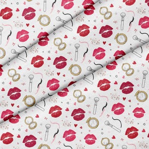 Puede incluir: Tela blanca con un patrón repetido de labios rojos, espejos compactos, brochas de maquillaje, corazones y diseños de pestañas. El diseño incluye acentos dorados, rosas y negros, creando un patrón con temática de belleza.