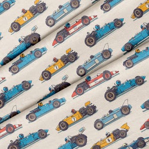 May include: A repeating pattern of vintage race cars in various colors, including yellow, blue, and red, with drivers wearing helmets. The cars are angled diagonally across a cream-colored background, creating a dynamic and energetic design.
