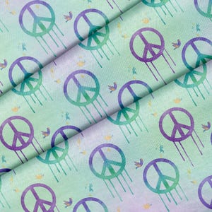 May include: Fabric featuring a repeating pattern of peace symbols in purple and teal, with dripping lines. Small bird and flower illustrations are scattered across a light green and purple gradient background.