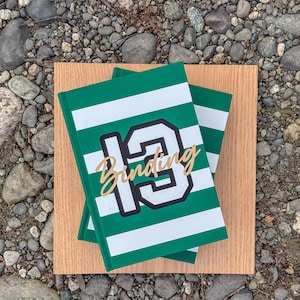 May include: Two green and white striped notebooks with a black and white number "19" and the word "Binding" in gold lettering.