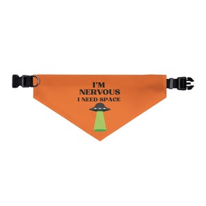 May include: Orange pet bandana with black buckle and ring hardware. The bandana features the text "I'M NERVOUS I NEED SPACE" with a graphic of a UFO and green beam.