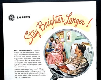 May include: Vintage advertisement for G.E. Lamps, featuring a retro illustration of a couple in a bedroom, viewed through a magnifying glass. The ad promotes brighter, longer-lasting light bulbs with the text "Stay Brighter Longer!" and product details.