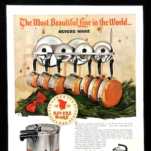 Puede incluir: Un juego de utensilios de cocina de acero inoxidable Revere Ware con fondos de cobre. El juego incluye una olla a presión, cacerolas, una tetera y una caldera doble. Los utensilios de cocina se muestran en un estante con un lazo rojo.
