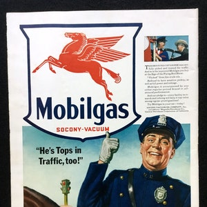 May include: A vintage Mobilgas advertisement featuring a red Pegasus logo above the text Mobilgas and Socony-Vacuum. Below, a police officer in a blue uniform gives a thumbs up next to the text He's Tops in Traffic, too! and a traffic light.