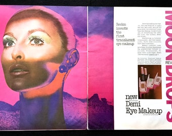 May include: Vintage Revlon advertisement for "MOONDROPS" Demi Eye Makeup. The image features a woman with dramatic eye makeup against a pink and purple background. The ad includes text about the product and its features.