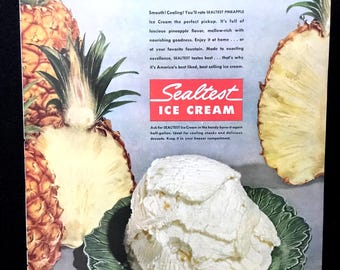May include: A vintage advertisement for Sealtest Pineapple Ice Cream featuring a scoop of white ice cream in a green leaf-shaped bowl, flanked by two pineapples. The text reads PINEAPPLE PERFECTION, Sealtest ICE CREAM, and Buy the best... buy Sealtest.