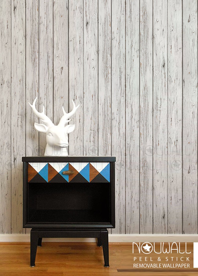 May include: Whitewashed wood peel and stick wallpaper with a black bedside table featuring a geometric pattern on the drawer. The bedside table has a white ceramic deer head on top. The text "NOWALL PEEL & STICK REMOVABLE WALLPAPER" is at the bottom of the image.