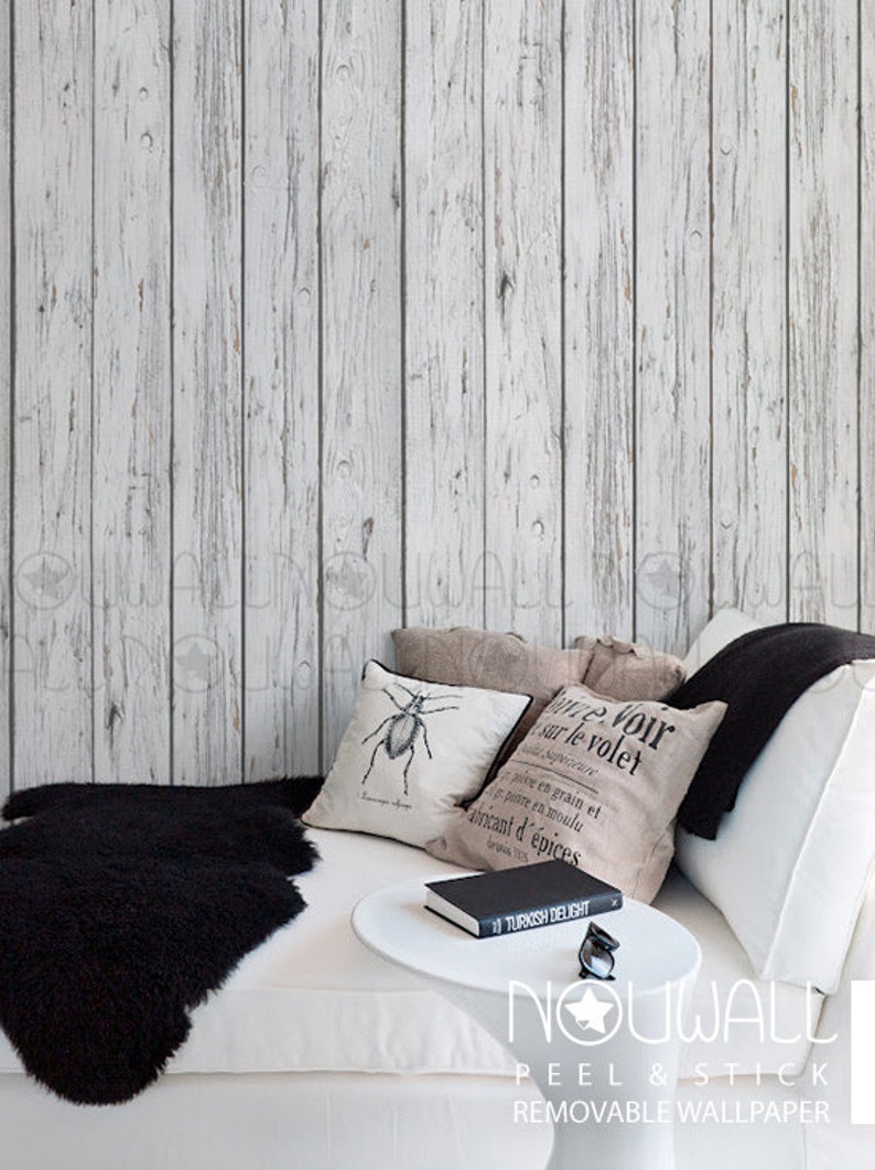 May include: White wood plank peel and stick wallpaper with a white sofa and black throw cushions. The text "NOUWALL PEEL & STICK REMOVABLE WALLPAPER" is visible at the bottom of the image.